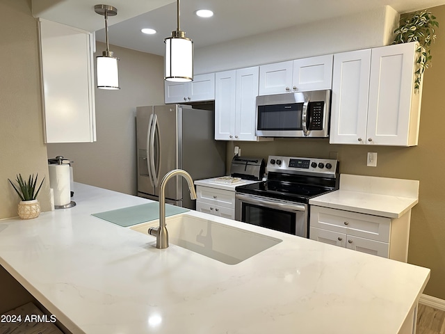 kitchen featuring white cabinetry, sink, decorative light fixtures, and stainless steel appliances