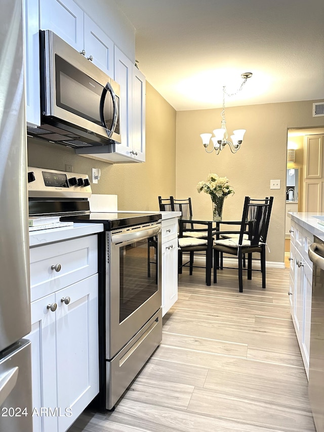 kitchen featuring white cabinetry, appliances with stainless steel finishes, an inviting chandelier, and pendant lighting