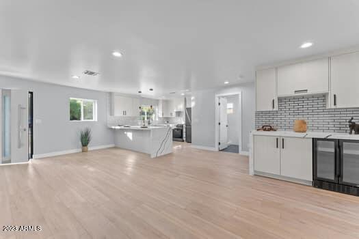 kitchen featuring white cabinets, decorative backsplash, light hardwood / wood-style floors, and kitchen peninsula