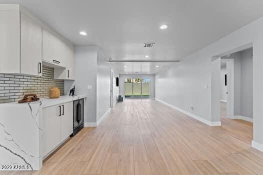 kitchen featuring light wood-type flooring, white cabinets, and decorative backsplash