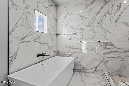 bathroom featuring tile walls and a bath