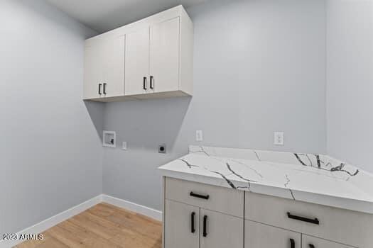 laundry room featuring light hardwood / wood-style flooring, hookup for an electric dryer, washer hookup, and cabinets