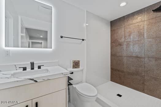 bathroom featuring vanity, toilet, and a tile shower