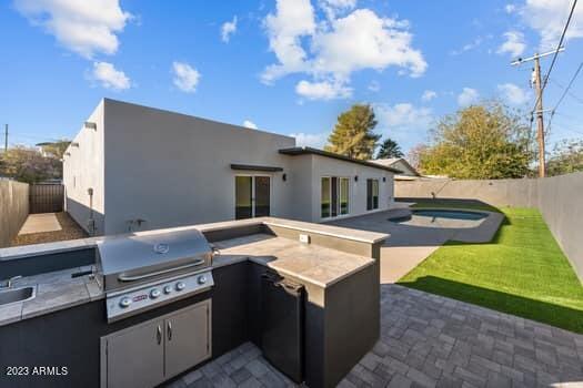 rear view of property featuring a yard, a patio area, and area for grilling