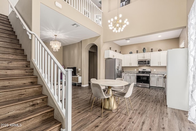 1367 S Country Club Dr Unit 1331, Mesa, AZ 85210 - dining space featuring a chandelier, a high ceiling, arched walkways, and wood finished floors
