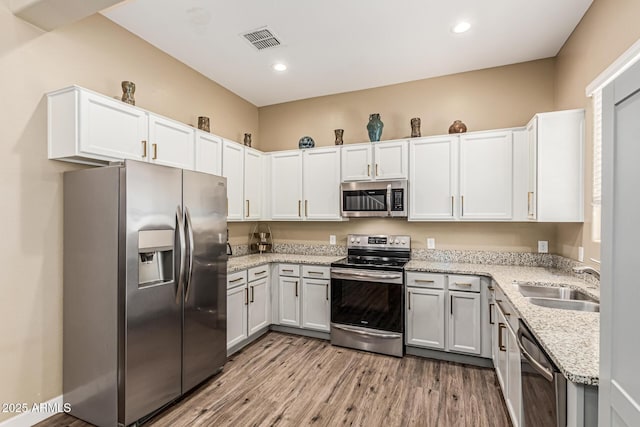 1367 S Country Club Dr Unit 1331, Mesa, AZ 85210 - kitchen featuring appliances with stainless steel finishes, light stone countertops, light wood finished floors, white cabinets, and recessed lighting