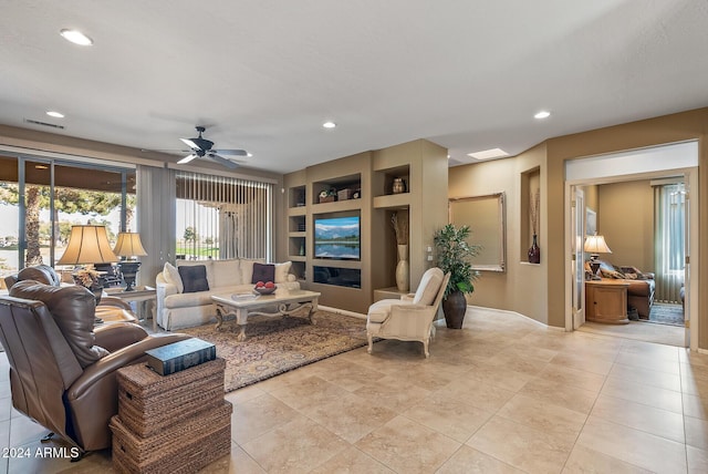 tiled living room featuring built in shelves and ceiling fan