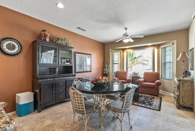 dining area featuring ceiling fan and a textured ceiling