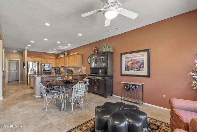 tiled dining space with ceiling fan and sink