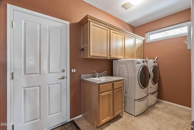 washroom featuring washing machine and dryer, sink, and cabinets