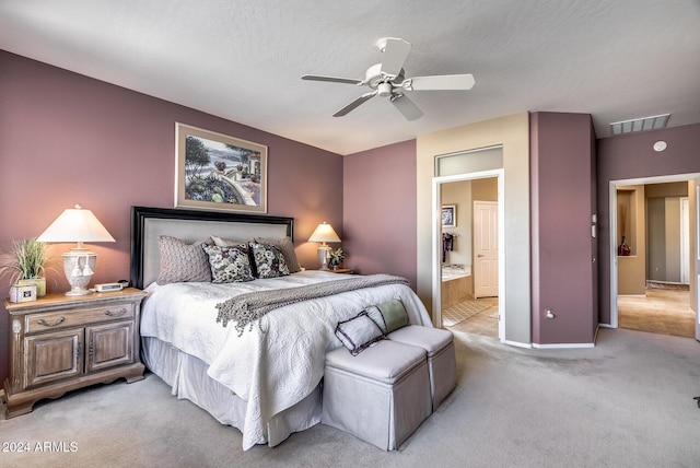 bedroom featuring ceiling fan, light colored carpet, a textured ceiling, and ensuite bath