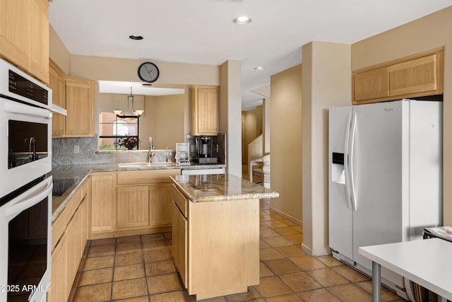 kitchen featuring a kitchen island, light brown cabinetry, decorative backsplash, white appliances, and a sink