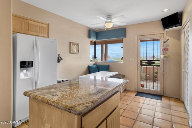 kitchen featuring a ceiling fan, light brown cabinets, a kitchen island, white fridge with ice dispenser, and light tile patterned floors