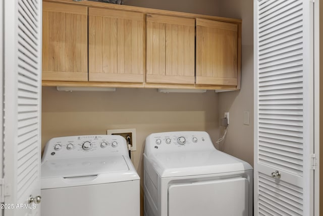 clothes washing area featuring cabinet space and washer and clothes dryer