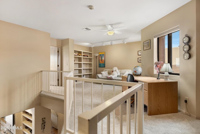 hallway featuring rail lighting, baseboards, visible vents, and light carpet