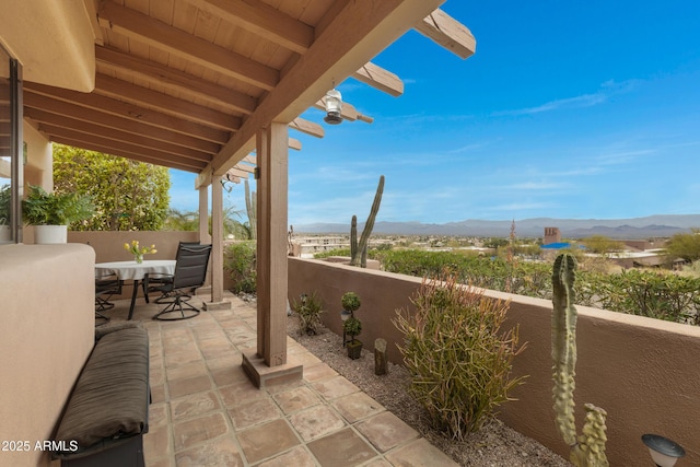 view of patio / terrace featuring outdoor dining area, fence, and a mountain view