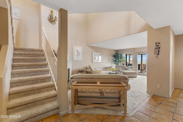 living area with a high ceiling, stairs, and baseboards