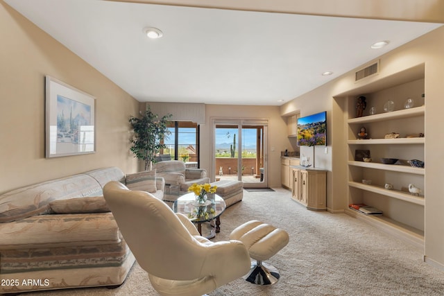 living area featuring visible vents, light colored carpet, built in shelves, and baseboards