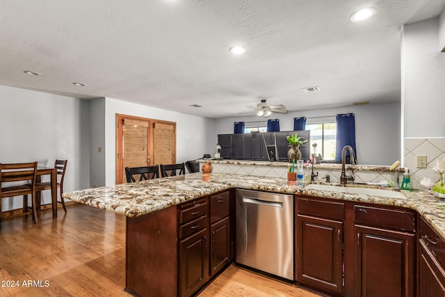 kitchen with kitchen peninsula, stainless steel dishwasher, tasteful backsplash, and light wood-type flooring