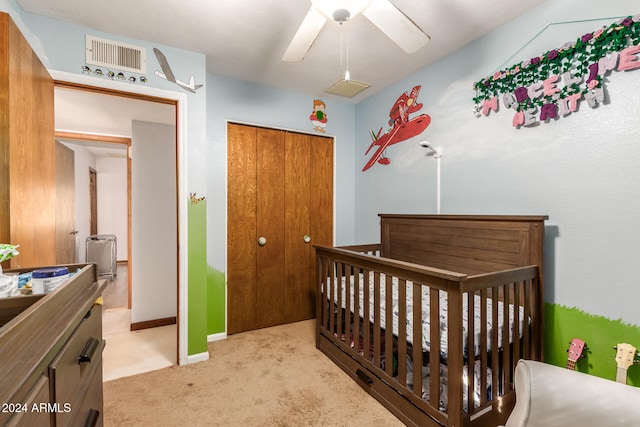 bedroom with ceiling fan, light carpet, a closet, and a nursery area