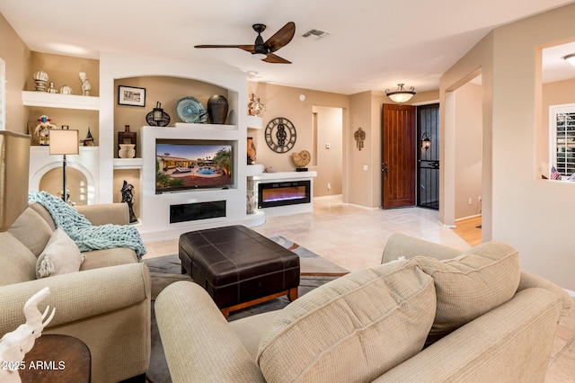 living room with built in shelves and ceiling fan