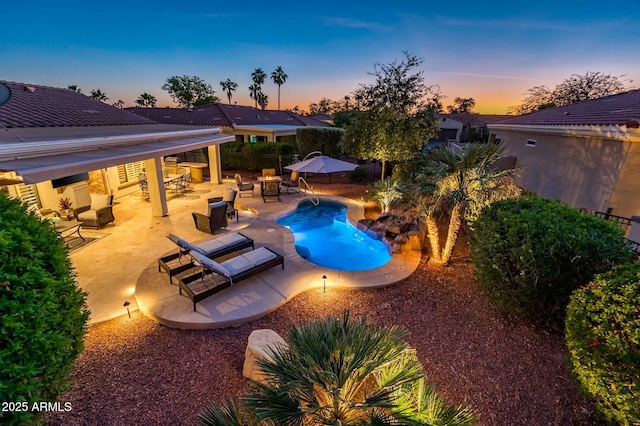 pool at dusk featuring a patio