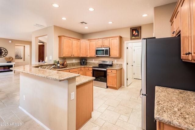 kitchen featuring kitchen peninsula, light stone counters, light brown cabinetry, and appliances with stainless steel finishes