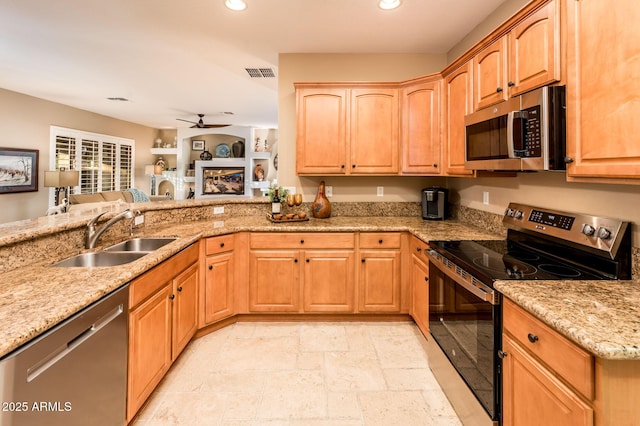 kitchen featuring ceiling fan, sink, stainless steel appliances, and light stone counters