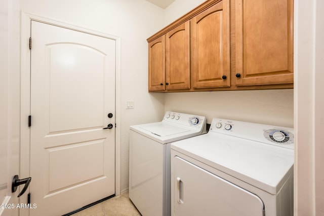 laundry area featuring washer and dryer, light tile patterned flooring, and cabinets