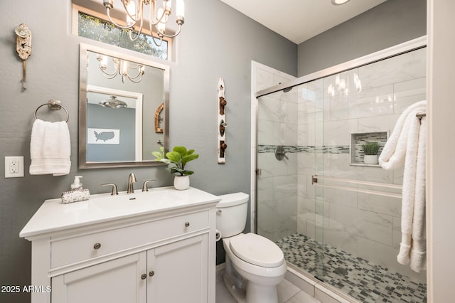 bathroom with toilet, vanity, an inviting chandelier, and a shower with door