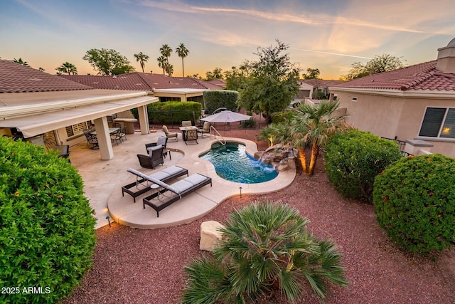 pool at dusk featuring a patio area