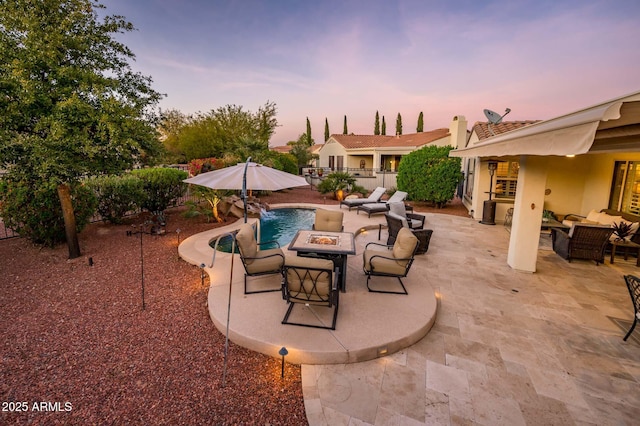 patio terrace at dusk featuring pool water feature and an outdoor living space with a fire pit