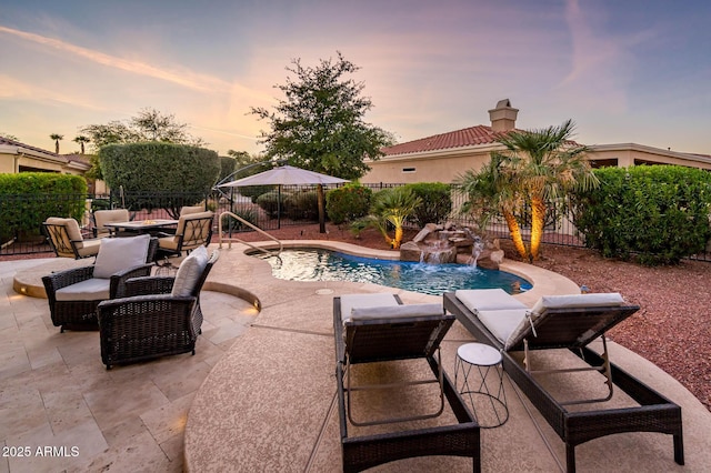 pool at dusk featuring pool water feature and a patio