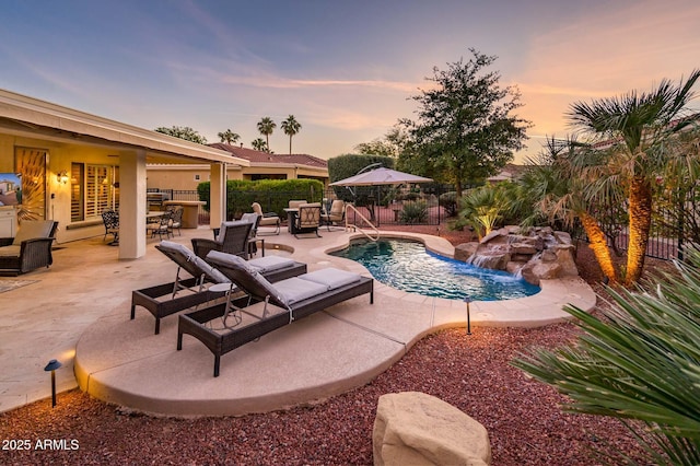 pool at dusk featuring a patio area and pool water feature