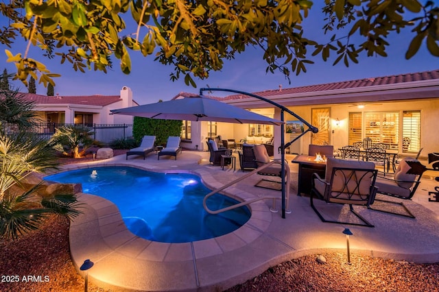 pool at dusk featuring a patio and an outdoor living space with a fire pit