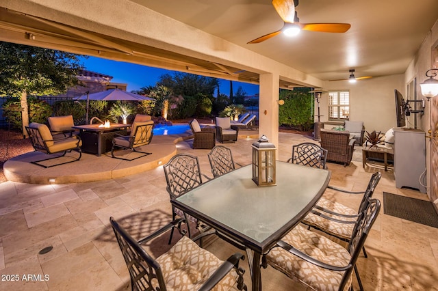 patio terrace at dusk featuring ceiling fan and an outdoor living space with a fire pit