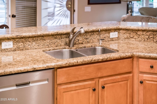 kitchen with light stone counters, stainless steel dishwasher, and sink