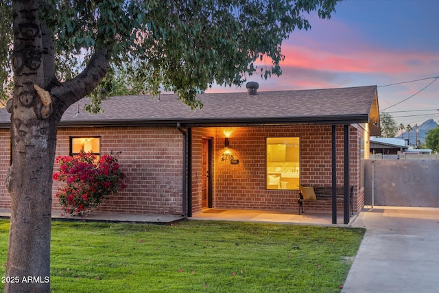 ranch-style house with concrete driveway, brick siding, a shingled roof, and a front yard