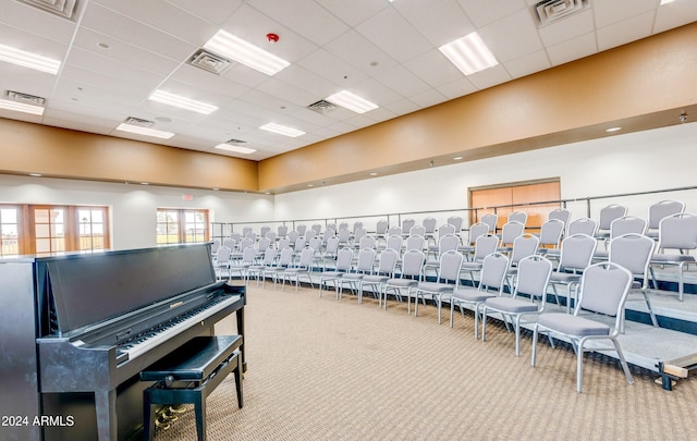 misc room featuring a paneled ceiling, a towering ceiling, and light colored carpet