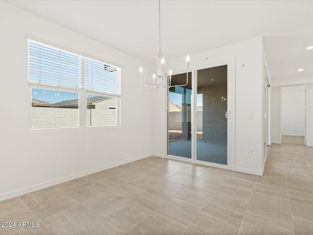 tiled empty room featuring an inviting chandelier