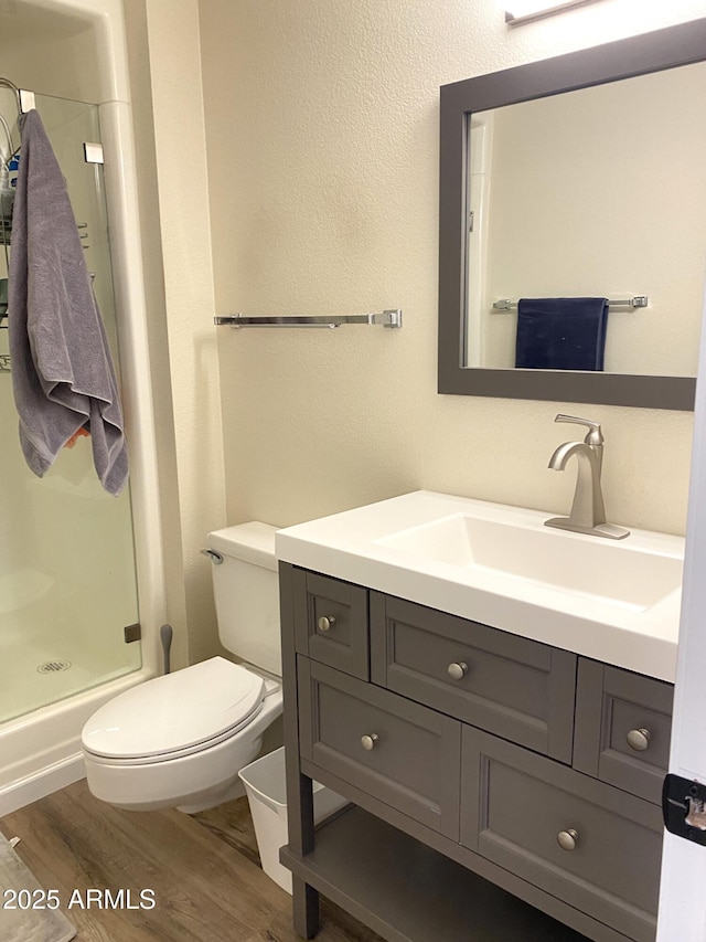 full bath with vanity, wood finished floors, toilet, and a shower stall