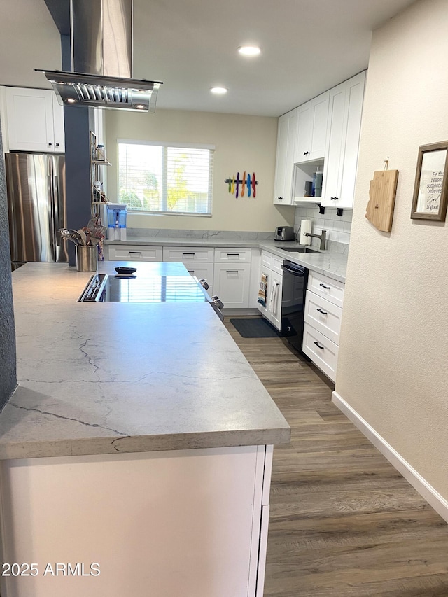 kitchen featuring black dishwasher, island exhaust hood, tasteful backsplash, freestanding refrigerator, and white cabinetry