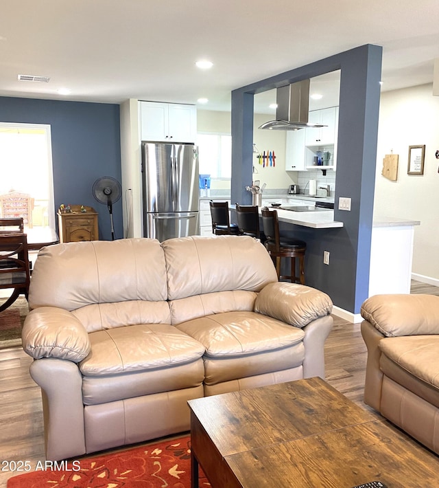 living area with recessed lighting, wood finished floors, visible vents, and baseboards