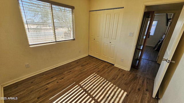 unfurnished bedroom with dark wood-type flooring and a closet