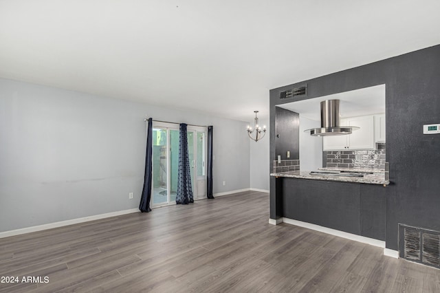 unfurnished living room featuring an inviting chandelier and dark hardwood / wood-style floors