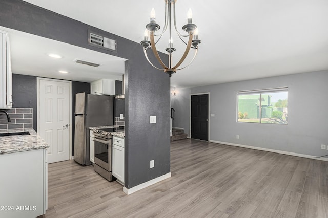 kitchen with sink, light stone counters, hanging light fixtures, appliances with stainless steel finishes, and white cabinets