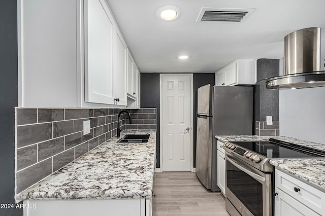 kitchen featuring sink, tasteful backsplash, white cabinets, stainless steel appliances, and wall chimney range hood