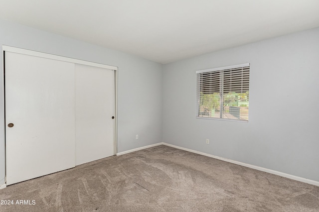 unfurnished bedroom with light colored carpet and a closet