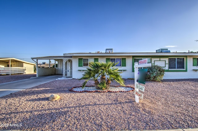 view of front of home featuring a carport, concrete driveway, and brick siding