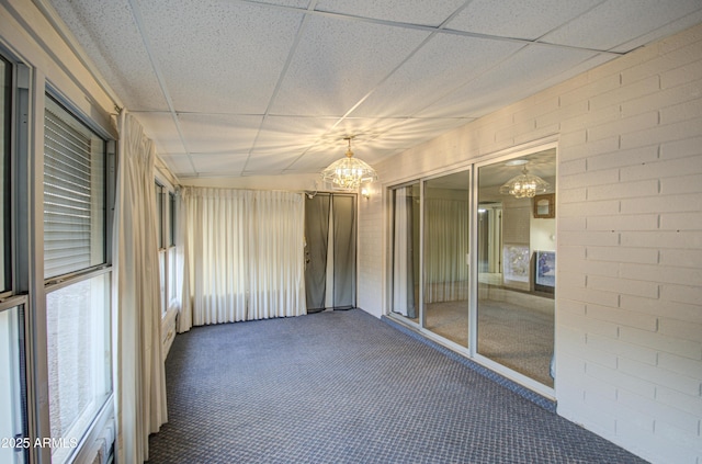 unfurnished sunroom featuring a chandelier and a drop ceiling